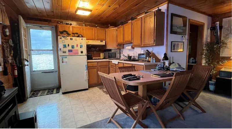 Slide: The Image of Cozy houseboat kitchen with wooden cabinets, dining table, and lake view. Custom model, 1990. - 7