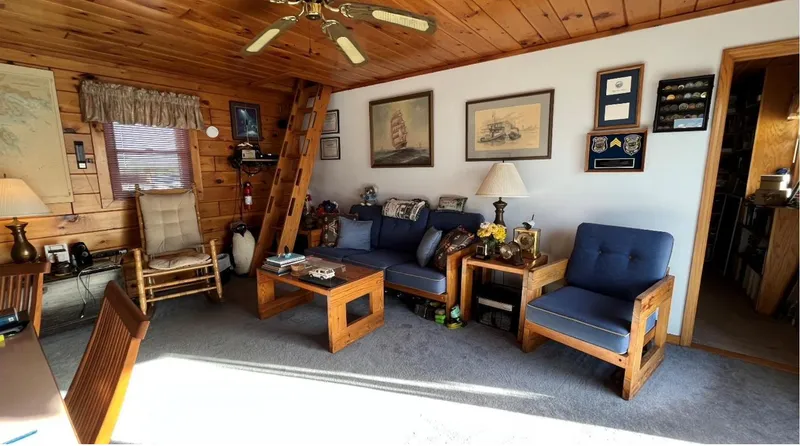 Slide: The Image of Cozy 1990 custom houseboat interior with wooden decor, blue seating, and nautical-themed wall art. - 8