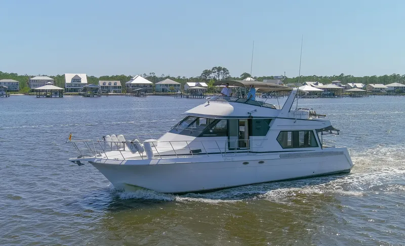 Slide: The Image of 1997 Navigator 5600 Sundance Pilothouse yacht cruising on a sunny day near waterfront homes. - 20