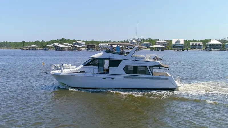 Slide: The Image of 1997 Navigator 5600 Sundance Pilothouse yacht cruising on a sunny day near waterfront homes. - 21