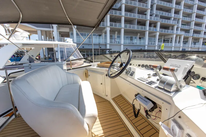 Slide: The Image of Navigator 5600 Sundance Pilothouse 1997 helm with white seating and control panel, docked near buildings. - 40