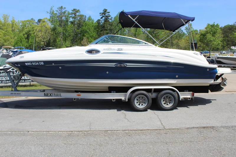 Slide: The Image of 2007 Sea Ray 240 Sundeck boat on trailer, parked outdoors with trees in background. - 1