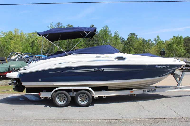 Slide: The Image of 2007 Sea Ray 240 Sundeck boat on trailer, blue and white, parked outdoors. - 27