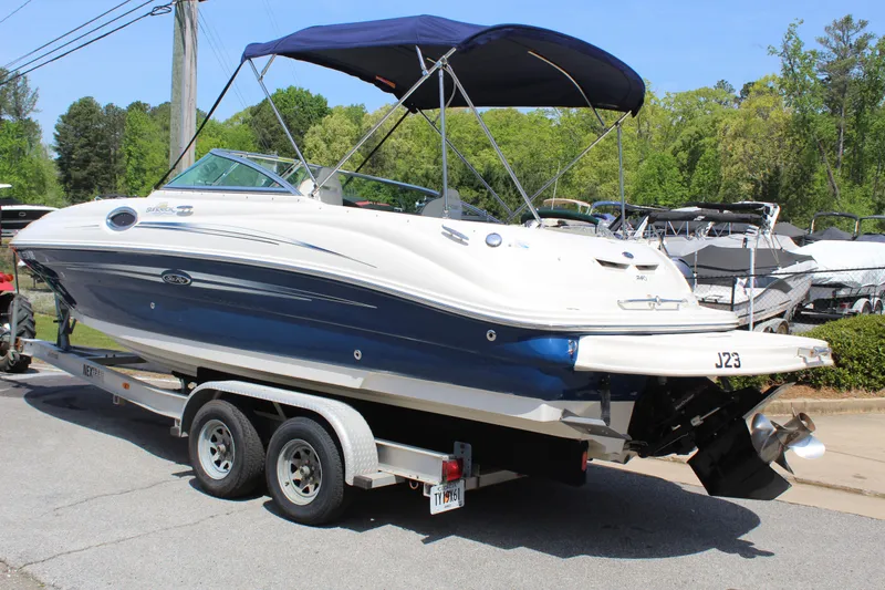 Slide: The Image of 2007 Sea Ray 240 Sundeck boat on trailer, blue and white, with canopy, parked outdoors. - 3