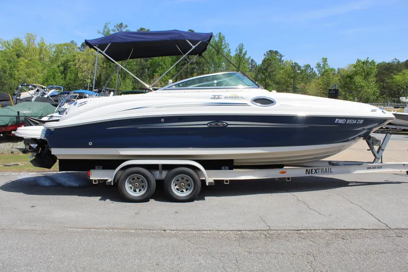 Slide: The Image of 2007 Sea Ray 240 Sundeck boat on trailer, parked outdoors with trees in background. - 6