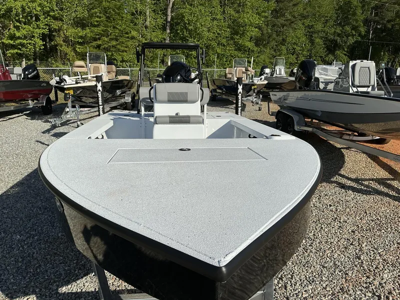 Slide: The Image of 2025 Xpress Skiff 185 boat displayed outdoors on gravel, surrounded by other boats. - 3