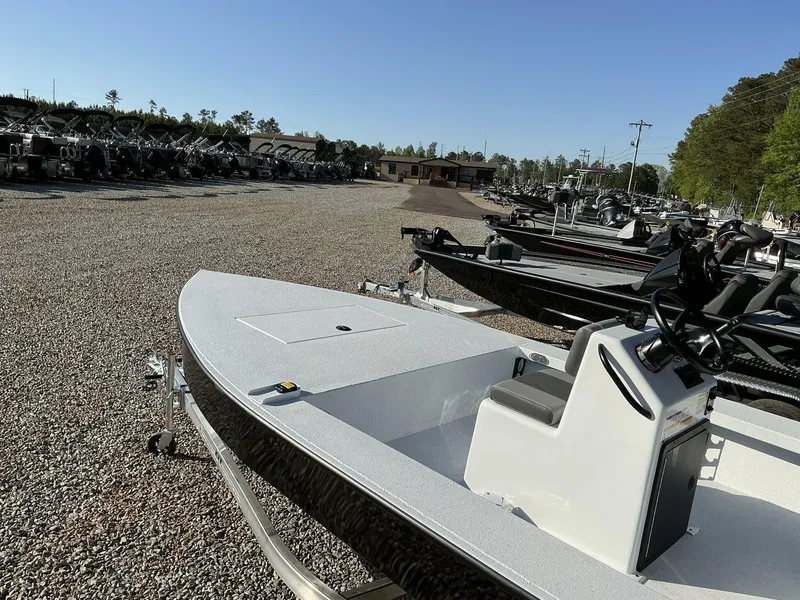 Slide: The Image of 2025 Xpress Skiff 185 boat displayed in a gravel lot with other boats. - 9