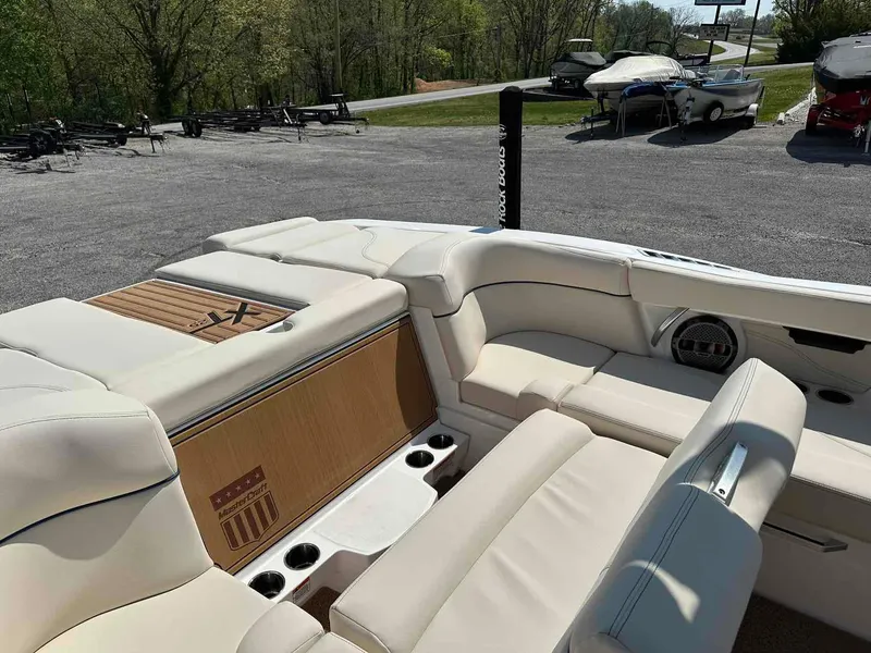 Slide: The Image of 2022 MasterCraft XT25 boat interior with beige seating and cup holders. - 13