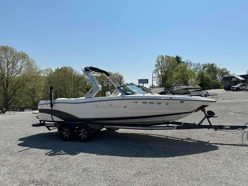 Slide: The Image of 2022 MasterCraft XT25 boat on trailer in sunny outdoor setting. - 4