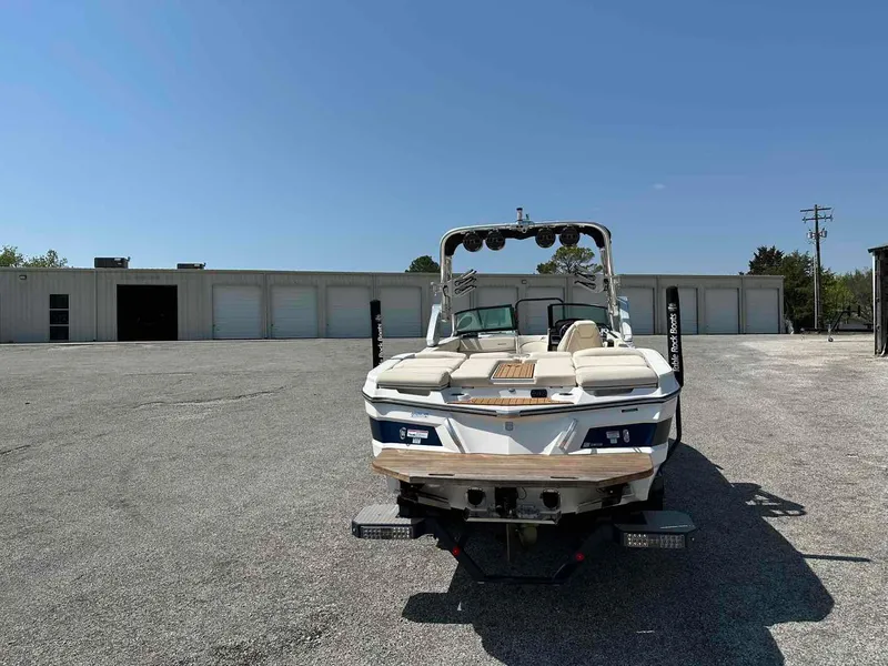 Slide: The Image of 2022 MasterCraft XT25 boat parked in an industrial lot under a clear blue sky. - 6