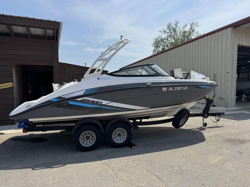 Slide: The Image of 2020 Yamaha AR210 boat on trailer, parked outside a building. - 0