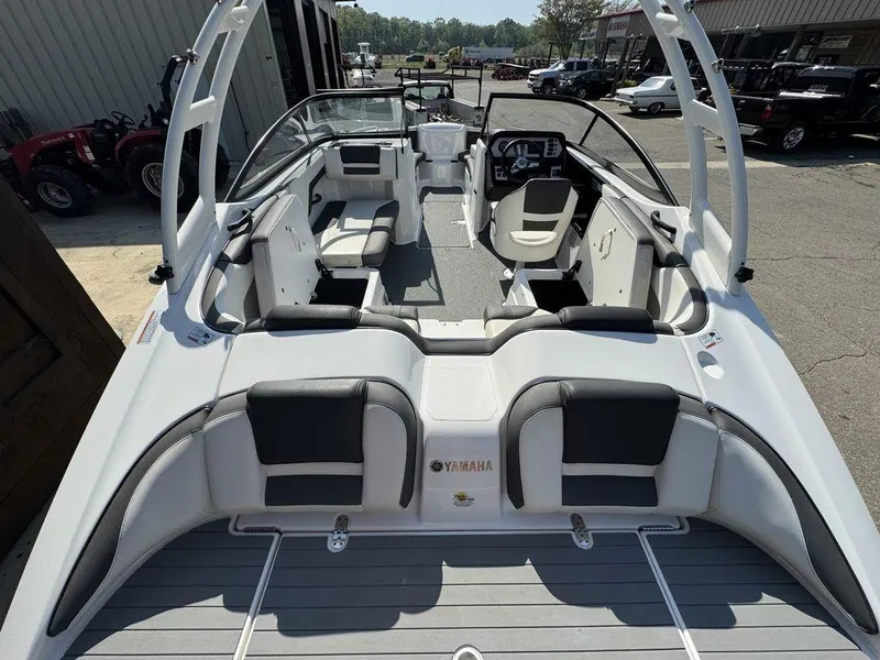 Slide: The Image of 2020 Yamaha AR210 boat interior with seating and steering wheel, parked outdoors. - 11