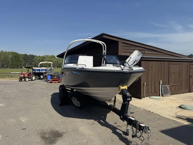 Slide: The Image of 2020 Yamaha AR210 boat on trailer near wooden shed, clear sky background. - 3