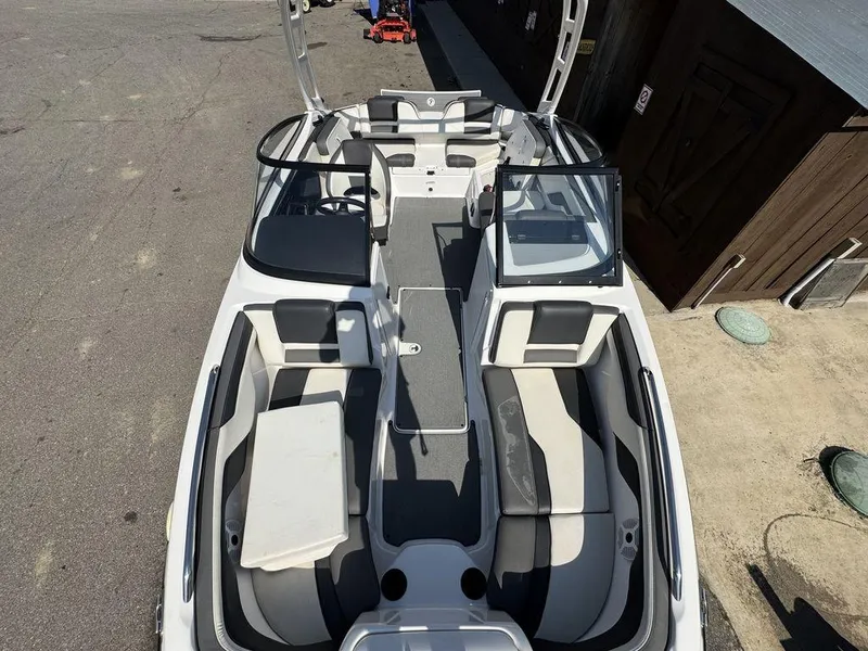 Slide: The Image of 2020 Yamaha AR210 boat interior with seating and steering wheel, parked on pavement. - 5