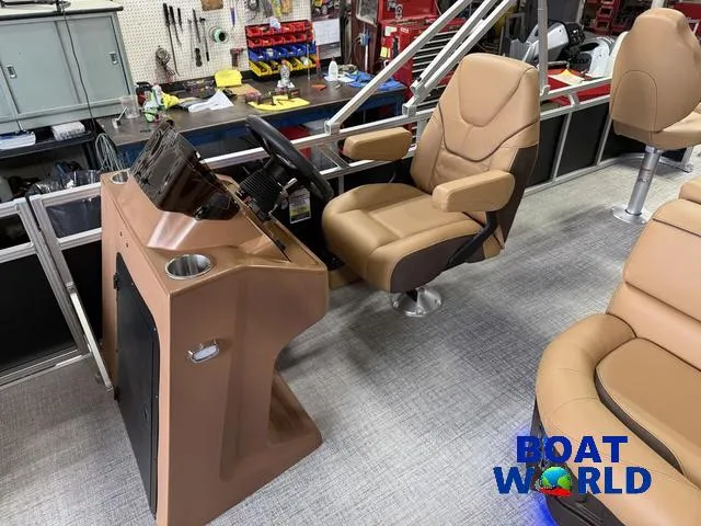 Slide: The Image of 2025 Tahoe Sport 2385 Tritoon interior with captain's chair and control console in workshop. - 11