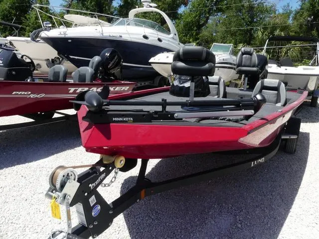 Slide: The Image of 2022 Lund 2175 Pro V fishing boat on trailer, parked among other boats. - 11