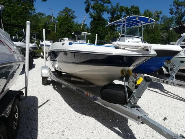 Slide: The Image of 2017 Stingray 182SC O/B boat on trailer, parked outdoors, surrounded by trees and other boats. - 2
