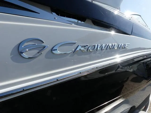 Slide: The Image of 2023 Crownline 290 XSS boat, sleek design with shiny logo detail. - 2