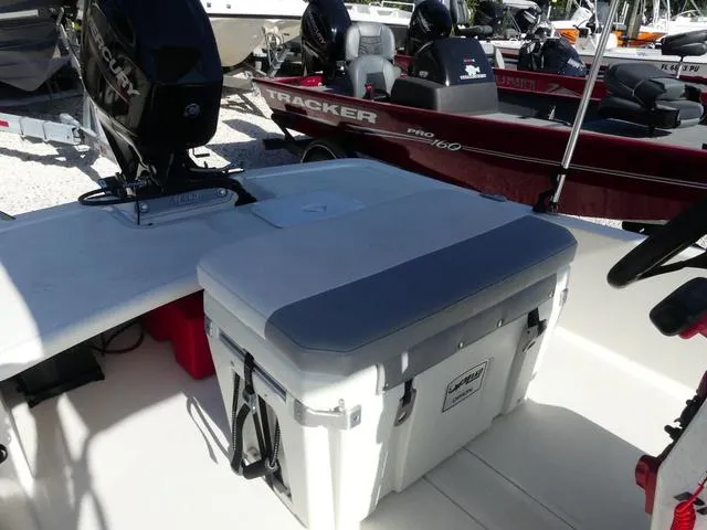 Slide: The Image of 2024 Mako Pro Skiff 15 CC boat interior with cooler and Mercury outboard motor. - 11