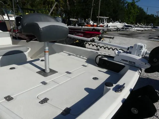 Slide: The Image of 2024 Mako Pro Skiff 15 CC boat with Minn Kota trolling motor, docked outdoors. - 13