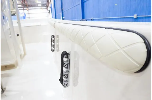 Slide: The Image of 2021 Carolina Skiff 21LS boat interior with padded railing and cleats in a warehouse setting. - 12