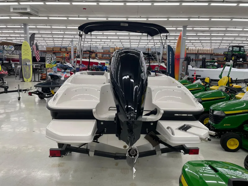 Slide: The Image of 2025 Bayliner Element E16 boat displayed indoors, surrounded by various equipment and vehicles. - 2