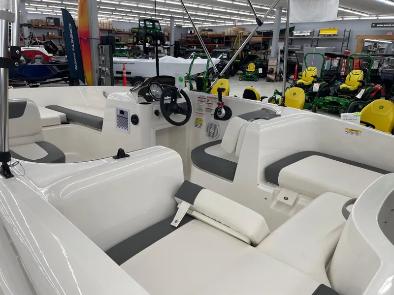 Slide: The Image of 2025 Bayliner Element E16 boat interior with seating and steering wheel in showroom. - 8
