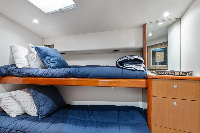 Slide: The Image of Bunk beds in a 2001 Viking Convertible yacht cabin with blue bedding and wooden cabinetry. - 32