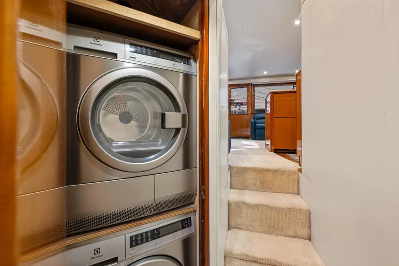 Slide: The Image of Laundry area inside a 2001 Viking Convertible yacht, featuring stacked washer and dryer units. - 34