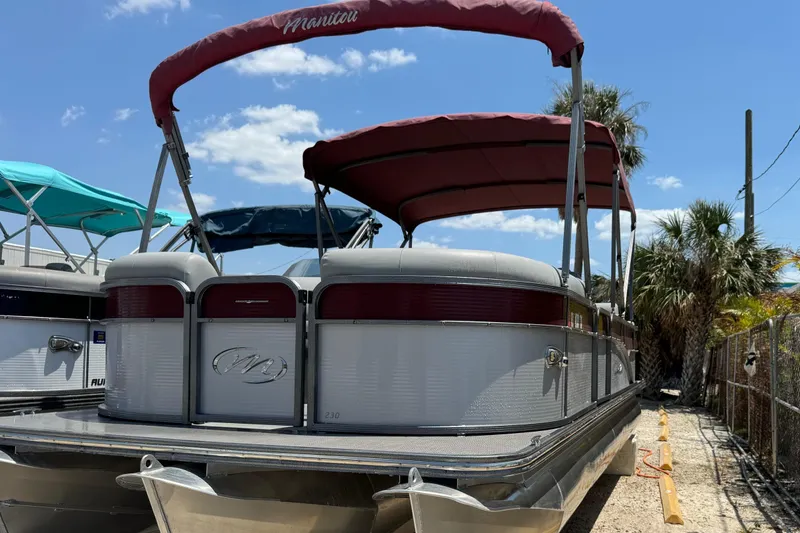 Slide: The Image of 2022 Manitou Oasis SR VP pontoon boat with red canopy, docked under a clear blue sky. - 18