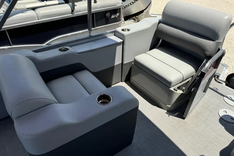 Slide: The Image of 2022 Manitou Oasis SR VP boat interior with gray seating and cup holders. - 3