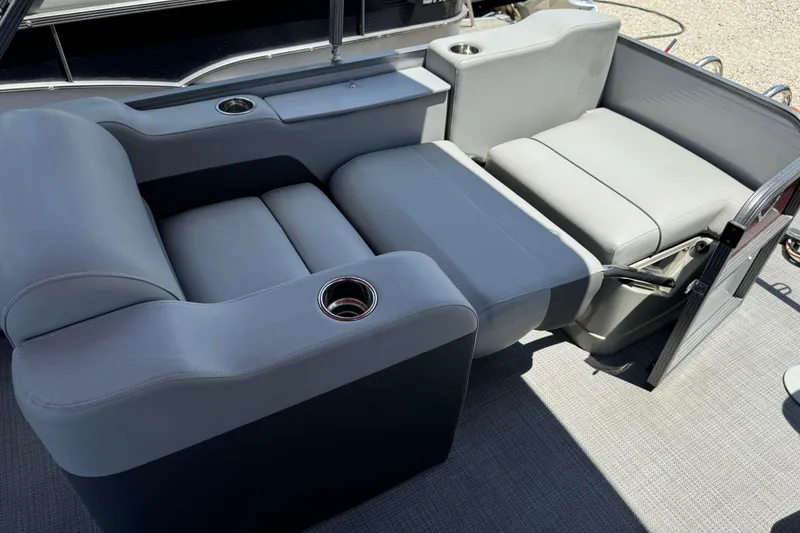 Slide: The Image of 2022 Manitou Oasis SR VP boat interior with gray seating and cup holders. - 4