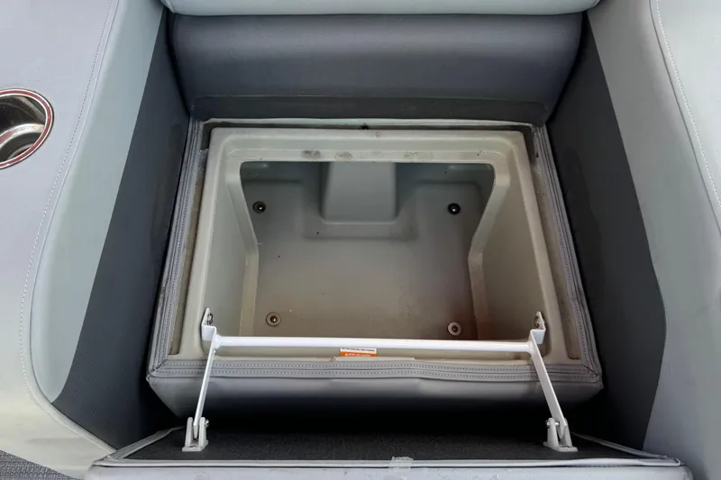 Slide: The Image of 2022 Manitou Oasis SR VP boat storage compartment with open lid, showcasing interior space. - 5