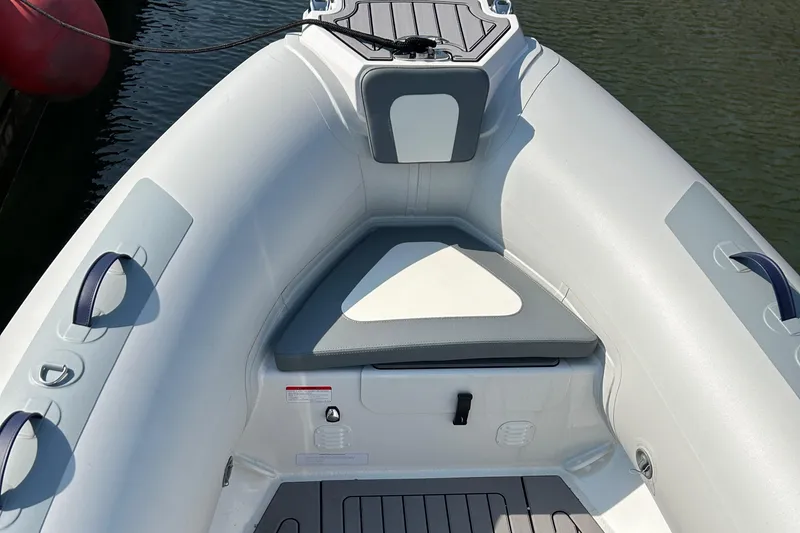 Slide: The Image of 2024 Highfield Classic 420 boat interior with cushioned seating and storage, docked on water. - 2