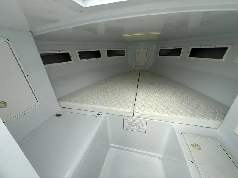 Slide: The Image of 2003 Strike 35 Cuddy cabin interior with white cushioned bedding and storage compartments. - 18