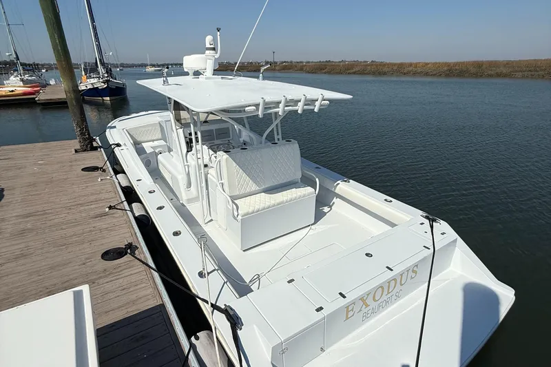 Slide: The Image of 2003 Strike 35 Cuddy boat docked by the water, featuring a spacious deck and seating. - 9