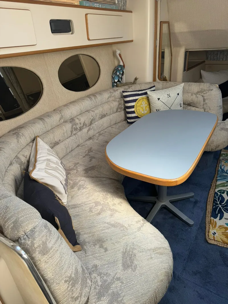 Slide: The Image of 1993 Sea Ray 370 Sundancer interior with curved seating, table, and nautical-themed decor. - 7