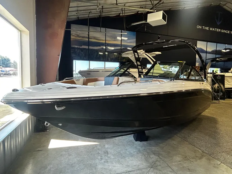 Slide: The Image of 2025 Chaparral 23 SSi boat displayed in showroom, sleek design, black and white exterior. - 2