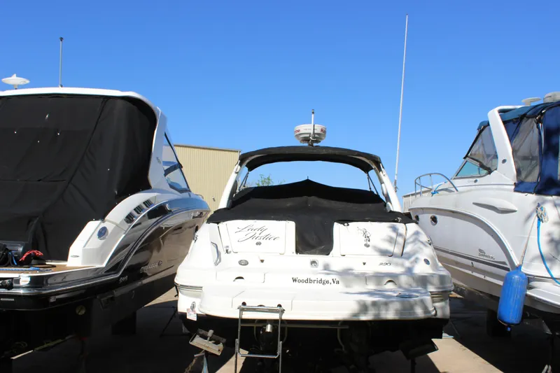 Slide: The Image of 2005 Sea Ray 290 Sundeck boat docked between two other boats under clear blue sky. - 6