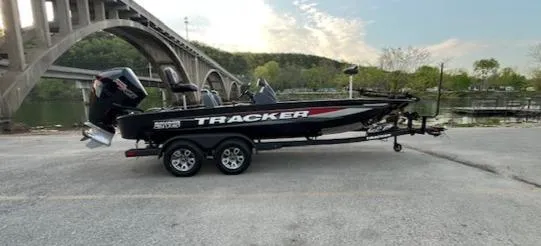 The Image of 2025 Tracker Savage 215 boat on trailer near bridge, scenic background. - 0
