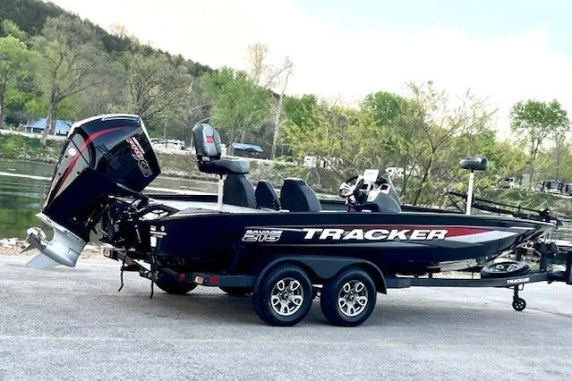 Slide: The Image of 2025 Tracker Savage 215 boat on trailer, parked near a scenic riverbank. - 111