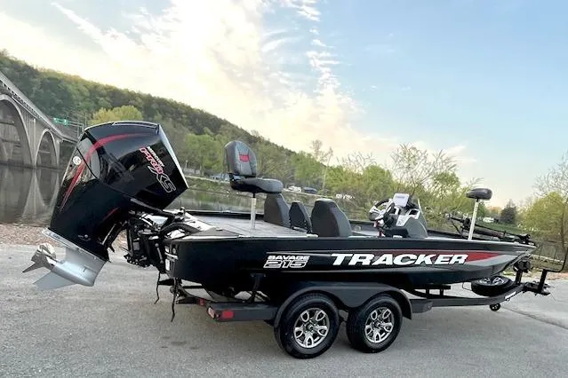 Slide: The Image of 2025 Tracker Savage 215 boat on trailer by a scenic riverside bridge. - 119