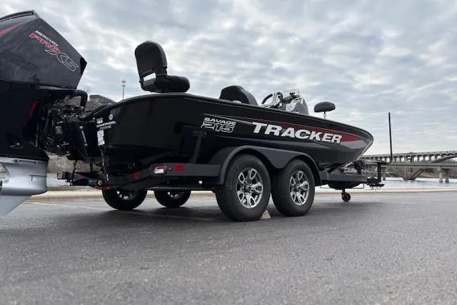 Slide: The Image of 2025 Tracker Savage 215 boat on trailer, parked near waterfront under cloudy sky. - 126