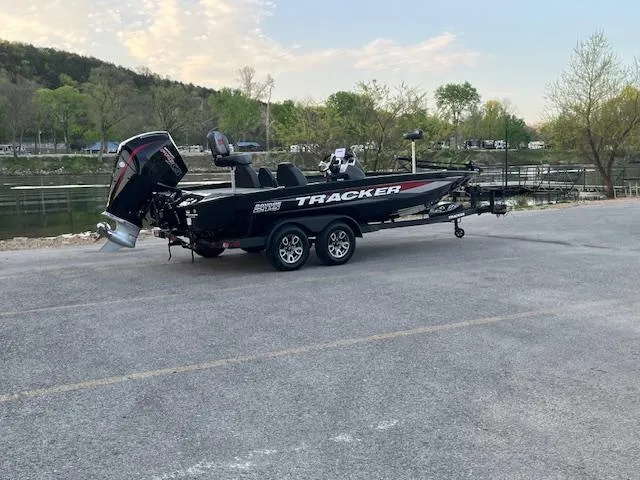 Slide: The Image of 2025 Tracker Savage 215 boat on trailer by river, under bridge, surrounded by trees. - 3