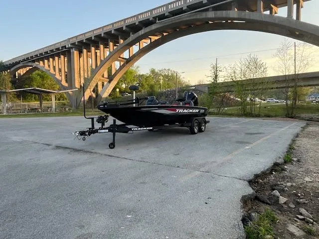 Slide: The Image of 2025 Tracker Savage 215 boat on trailer near a bridge, ready for water adventure. - 4