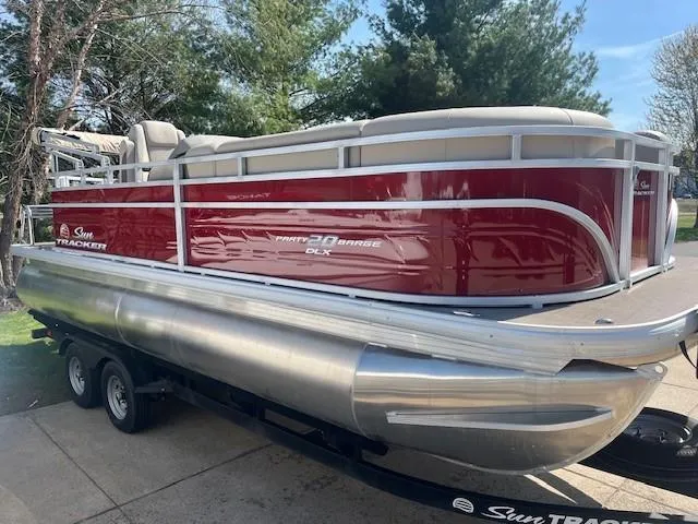 Slide: The Image of 2025 Sun Tracker Party Barge 20 DLX pontoon boat on trailer, red and silver design. - 6