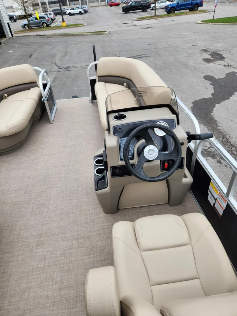 Slide: The Image of 2025 Sun Tracker Party Barge 16 DLX interior with beige seating and steering console. - 4