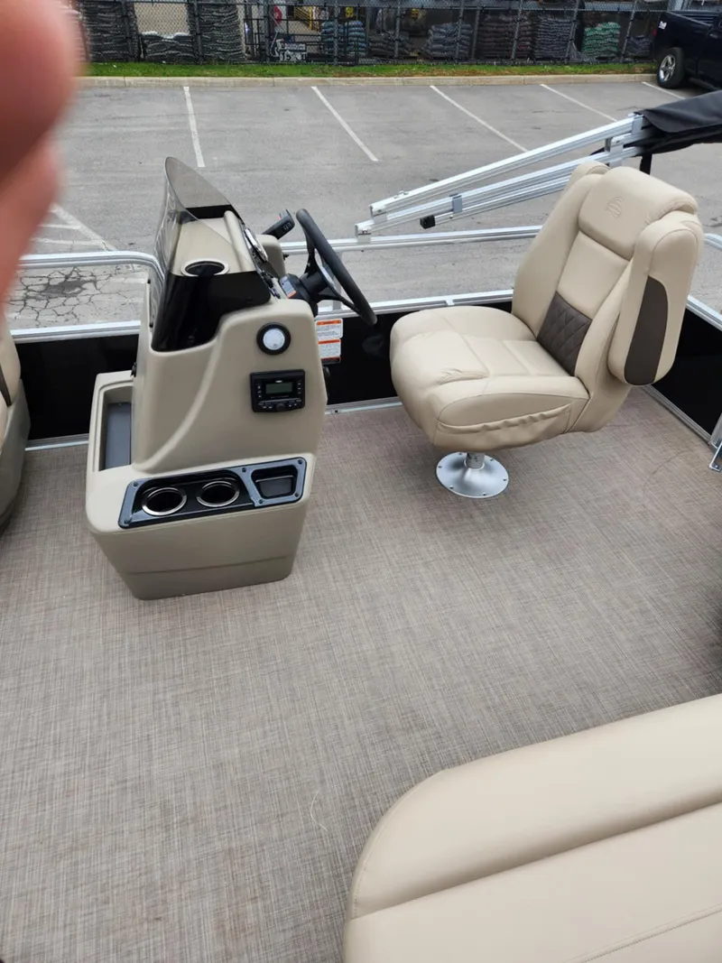 Slide: The Image of 2025 Sun Tracker Party Barge 16 DLX interior with beige seating and steering console. - 5