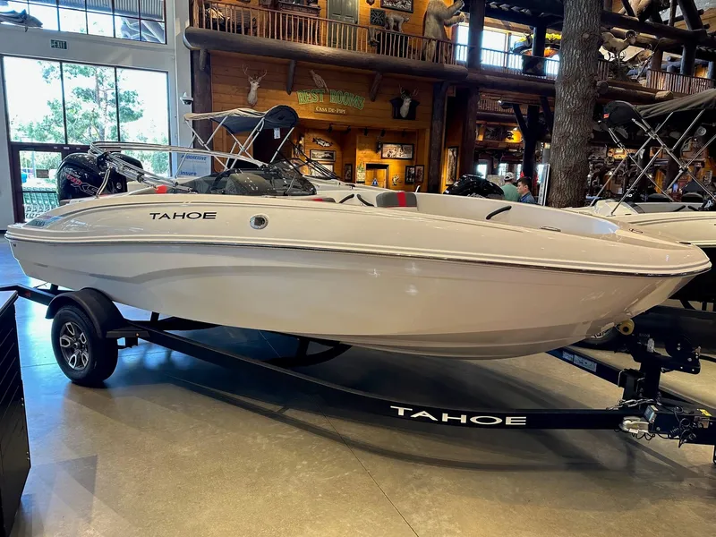 The Image of 2025 Tahoe T18 boat on trailer in showroom, sleek design, white exterior. - 0
