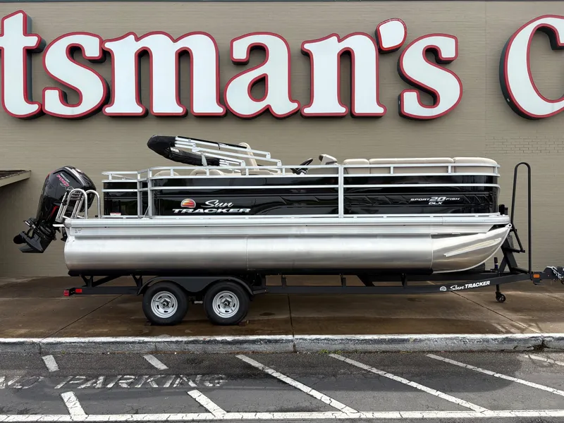 The Image of 2025 Sun Tracker SportFish 20 DLX pontoon boat on trailer, parked outside a store. - 0